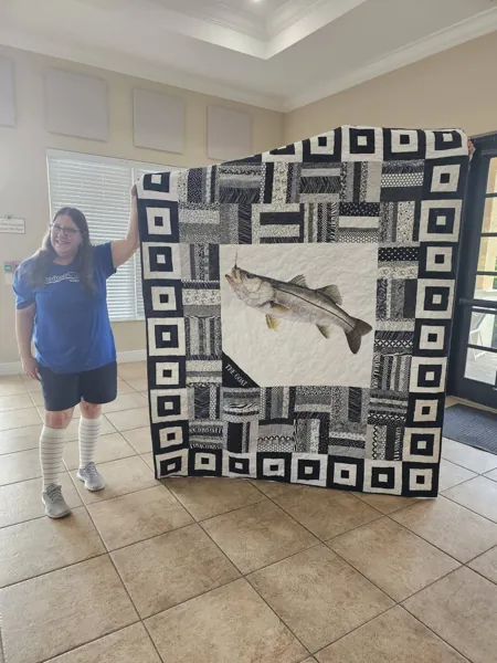 Volunteers displaying a black and white quilt with an animal panel