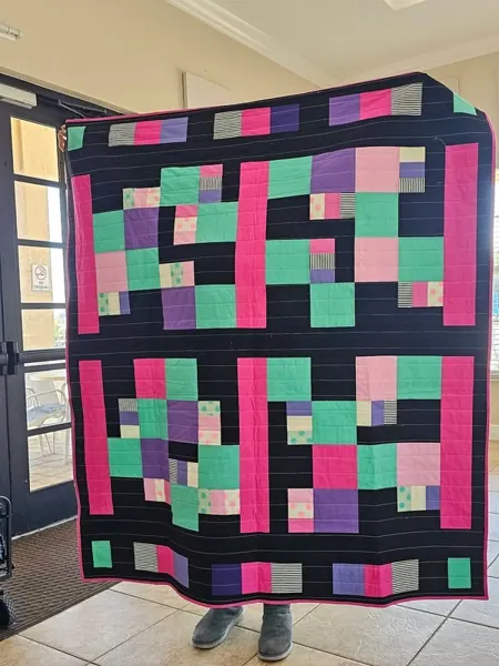 Bright geometric quilt with pink green and blue blocks