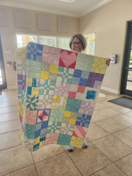 Volunteer holding a colorful patchwork quilt