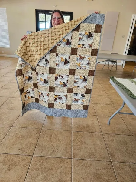 Volunteer displaying a cream and brown patchwork quilt