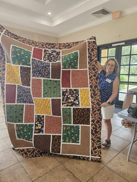 Volunteers holding a quilt with multicolored patterned panels