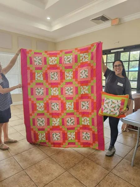 Volunteers displaying a red floral quilt